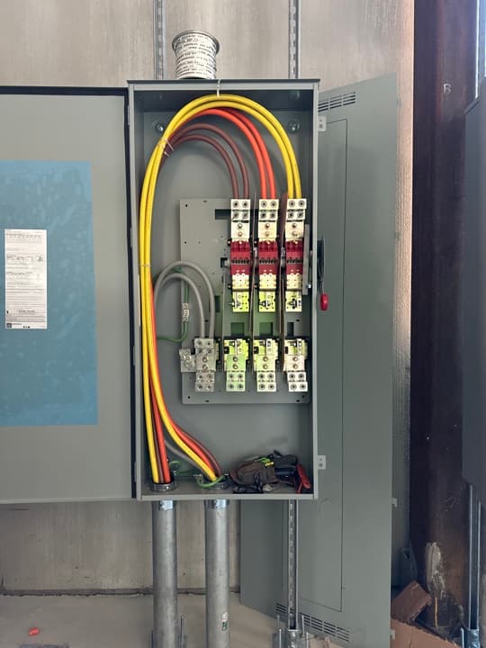 Large commercial three-phase distribution and disconnect with high-amp feeders dressed neatly inside the enclosure.