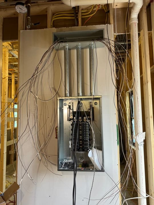 New-construction whole-house panel rough-in with three EMT chases feeding from above and homerun cables fanned out below.