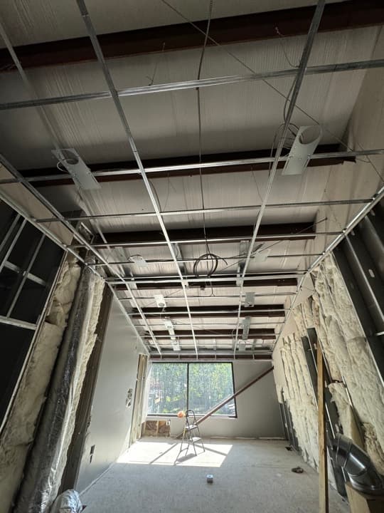 Commercial fit-out with metal-stud framing, overhead conduit, and rough-ins through the studs.