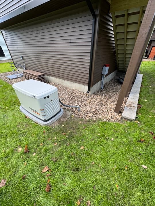 Generac whole-home generator viewed from the yard alongside the gas regulator.