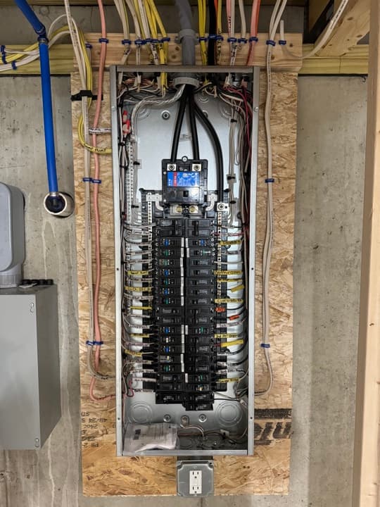 Commercial sub-panel during install with breakers organized in pairs, neutrals and grounds dressed onto the bus.