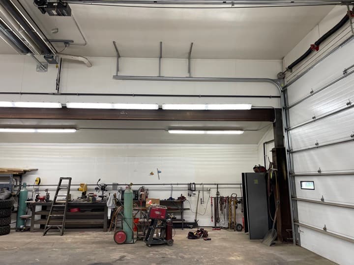 Workshop or garage interior with continuous LED strip lighting running across two bays.